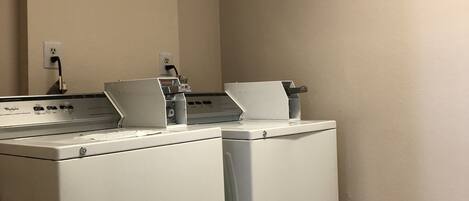 A laundry area with two front-loading washing machines and a dryer.