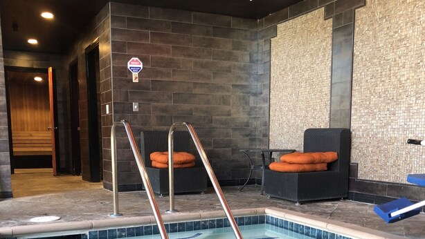 A swimming pool with a metal ladder, a bench, and a wall with a textured pattern. - Hotel Le Rêve Pasadena (Pasadena)