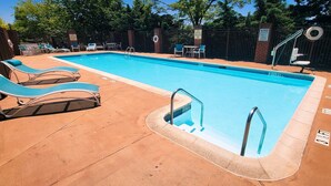A rectangular swimming pool with a 4 FT depth, surrounded by lounge chairs and a brick wall. - Holiday Inn Express - Harrisburg East by IHG (Harrisburg)
