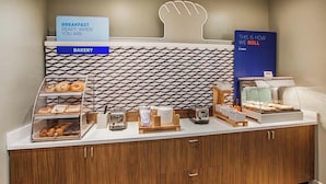A breakfast station with a bakery section, a coffee machine, and a display case with pastries. - Holiday Inn Express - Harrisburg East by IHG (Harrisburg)