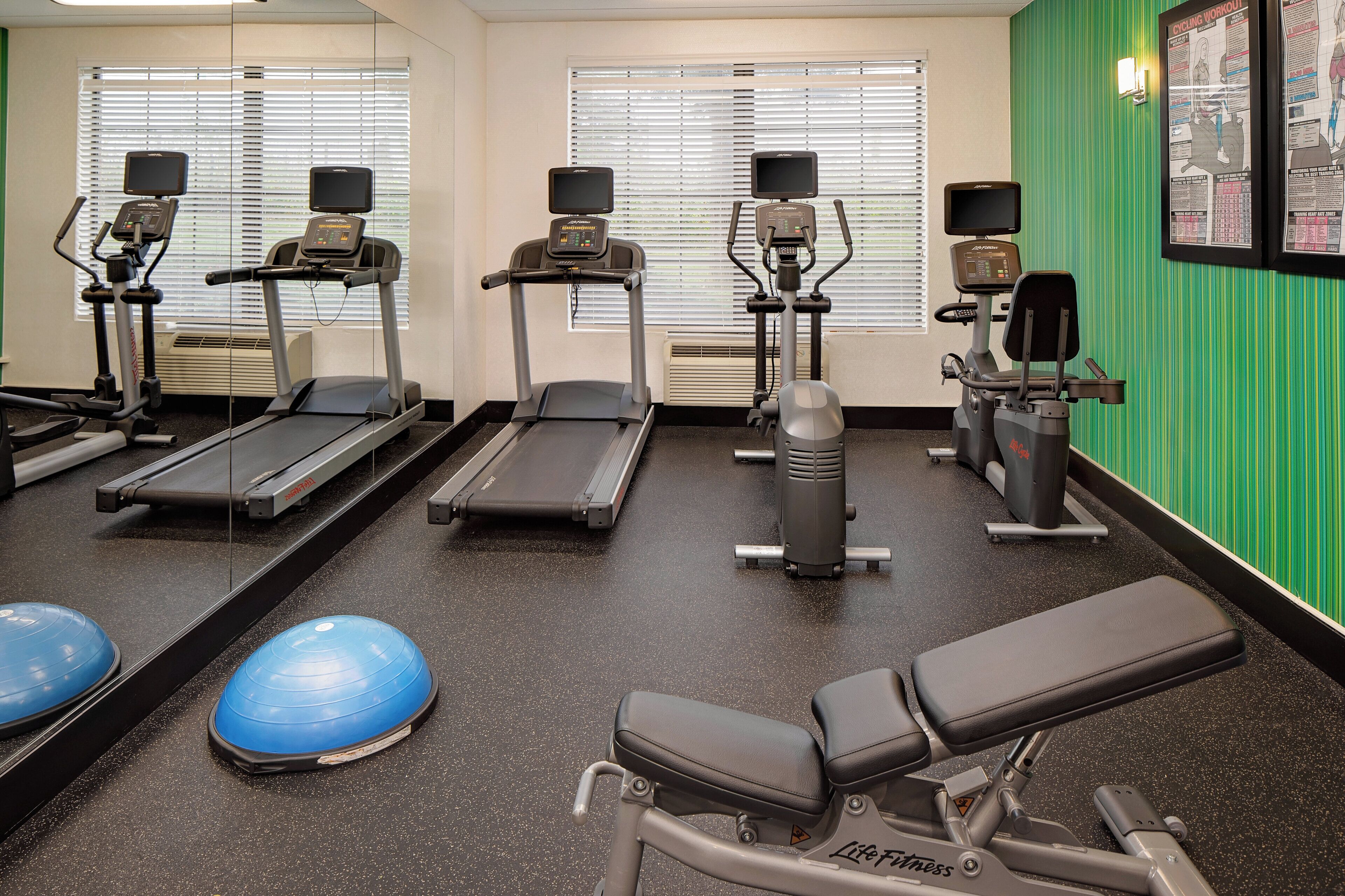 A gym with treadmills, elliptical machines, and exercise balls.