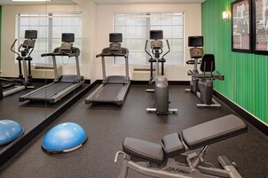 A gym with treadmills, elliptical machines, and exercise balls.