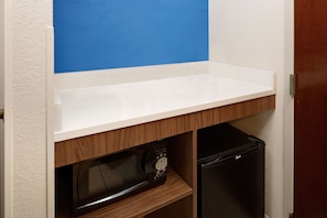 Una cocina con microondas y un refrigerador negro.