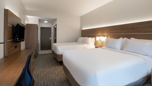 A hotel room with two beds, a desk, a television, and a door leading to another room. - Holiday Inn Express - Harrisburg East by IHG (Harrisburg)