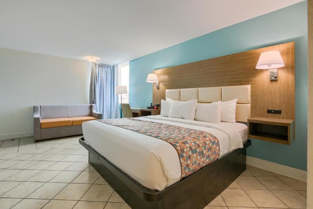Ein Hotelzimmer mit einem Bett, einer Couch, einem Nachttisch und einer Wandleuchte.
