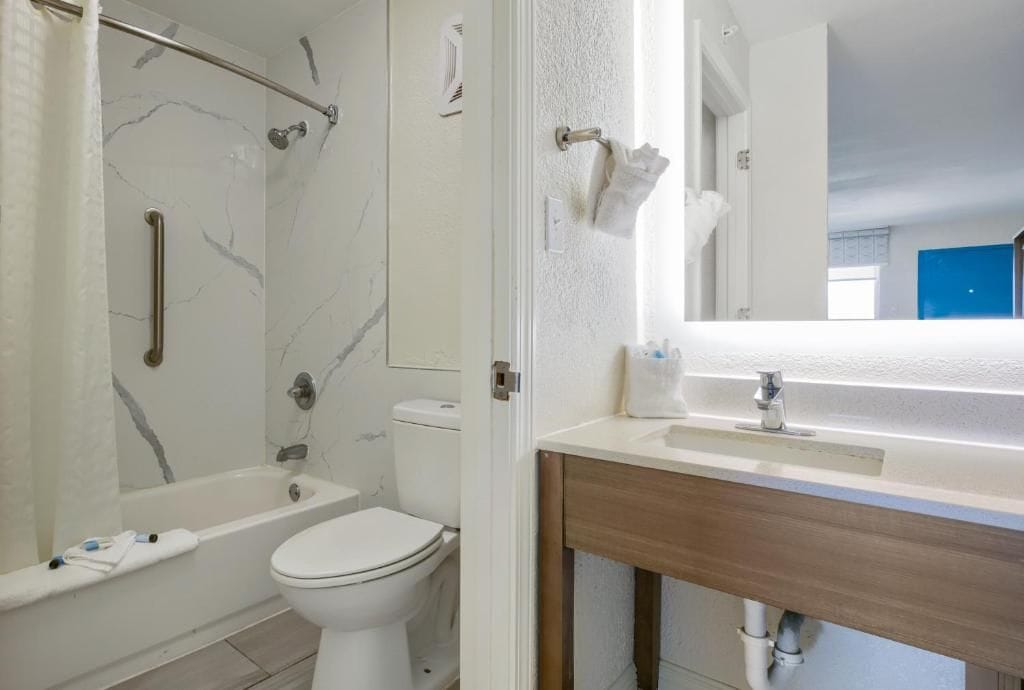 Ein Badezimmer mit Badewanne, Toilette und Waschtisch mit Spiegel.