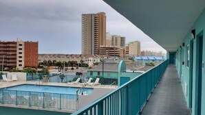 A balcony with a pool, overlooking a cityscape with tall buildings.