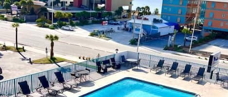A swimming pool with lounge chairs and a view of tall buildings in the background.