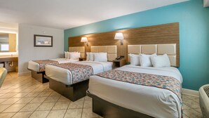 A hotel room with two beds, a wooden headboard, and a blue accent wall.