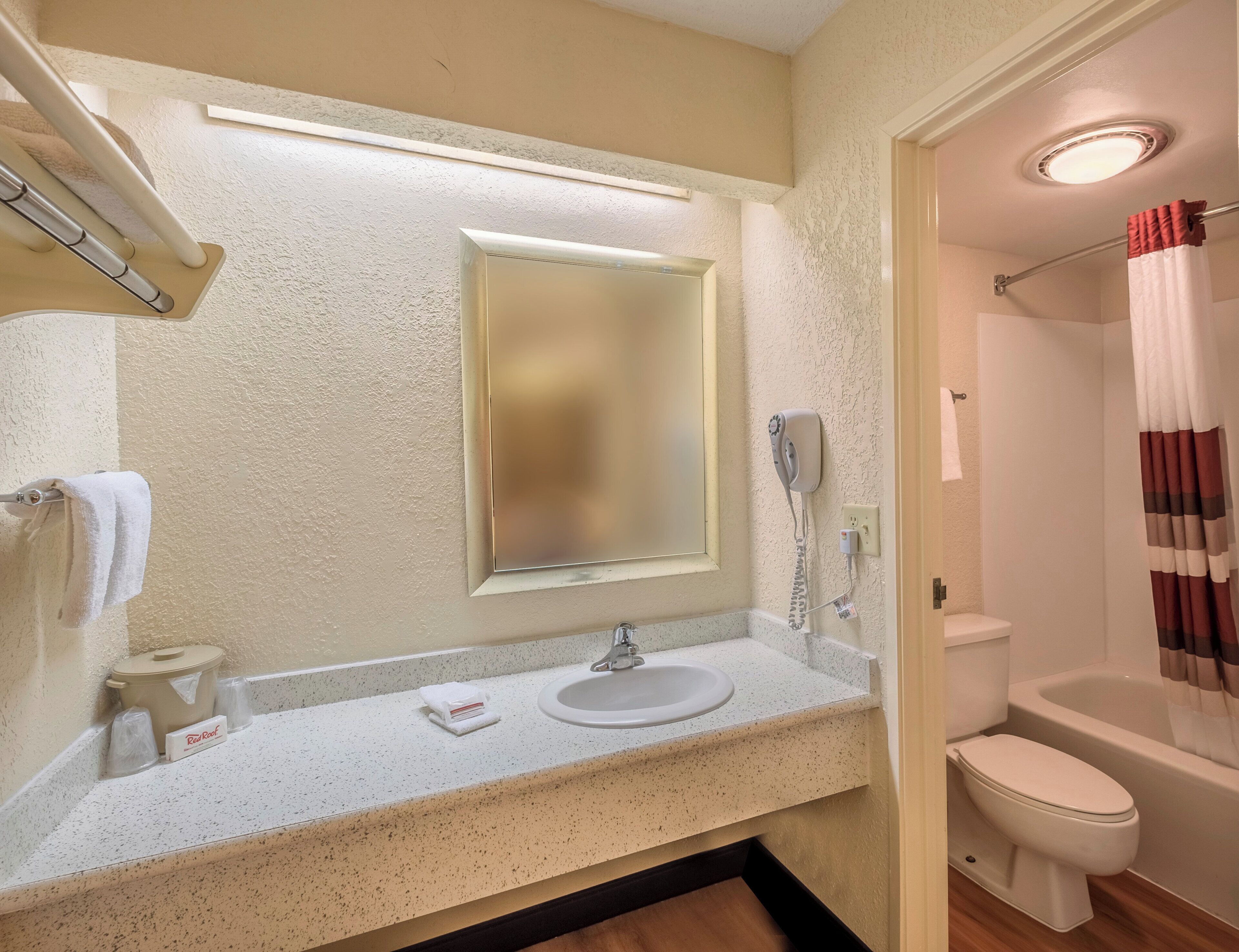 Ein Badezimmer mit Waschbecken, Spiegel, Toilette und Duschvorhang.