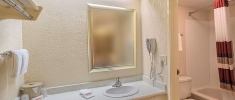 A bathroom with a sink, mirror, toilet, and shower curtain.