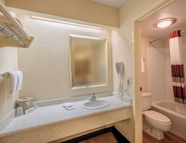 Ein Badezimmer mit Waschbecken, Spiegel, Toilette und Duschvorhang.