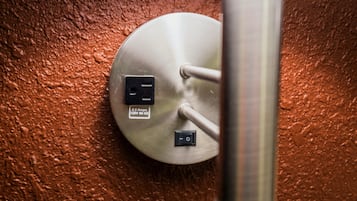 A metallic electrical outlet with a label indicating '3.2 Amps 120V 60Hz' on a textured wall.