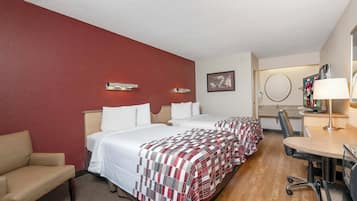 A hotel room with two beds, a desk, a chair, and a television.