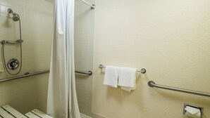 A bathroom with a shower, grab bars, a towel rack, and a toilet paper holder. - Red Roof Inn Indianapolis South (Indianapolis)