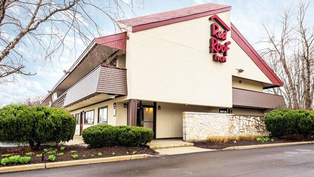 Un Red Roof Inn con una estructura de dos pisos, fachada de piedra y techo rojo.