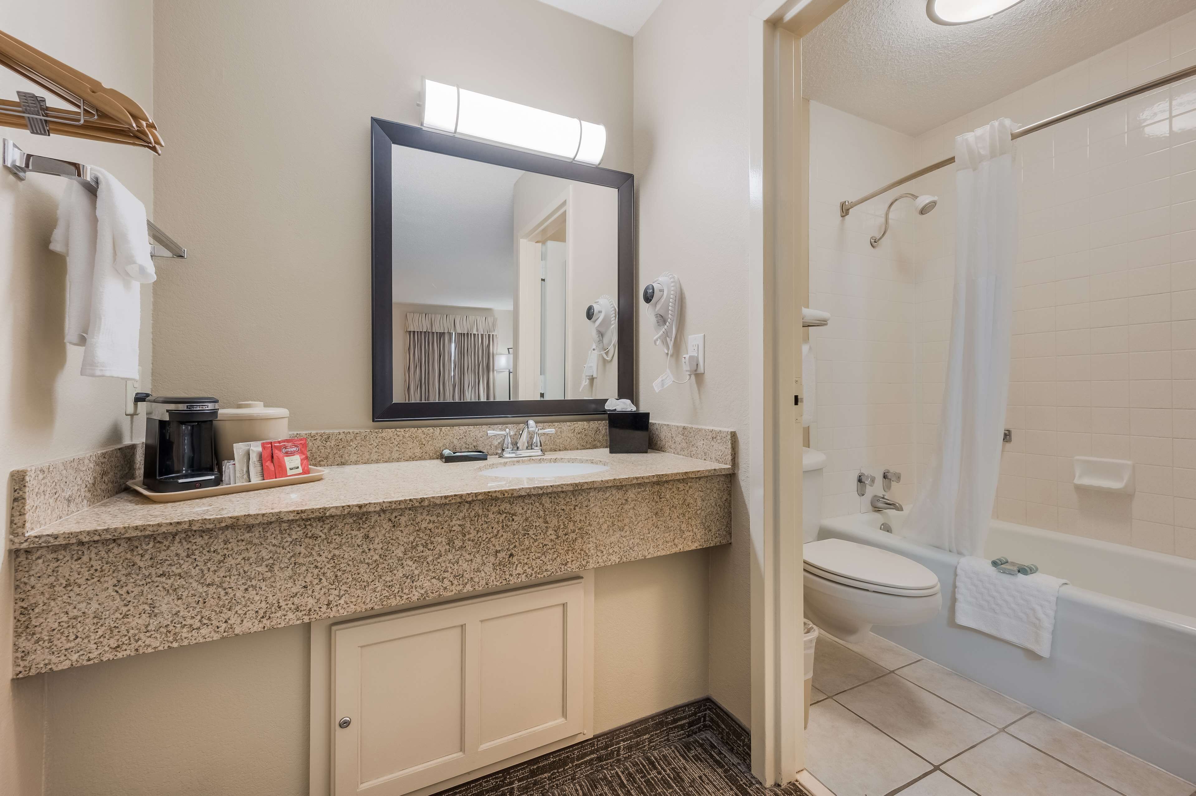 A bathroom with a sink, mirror, and shower.