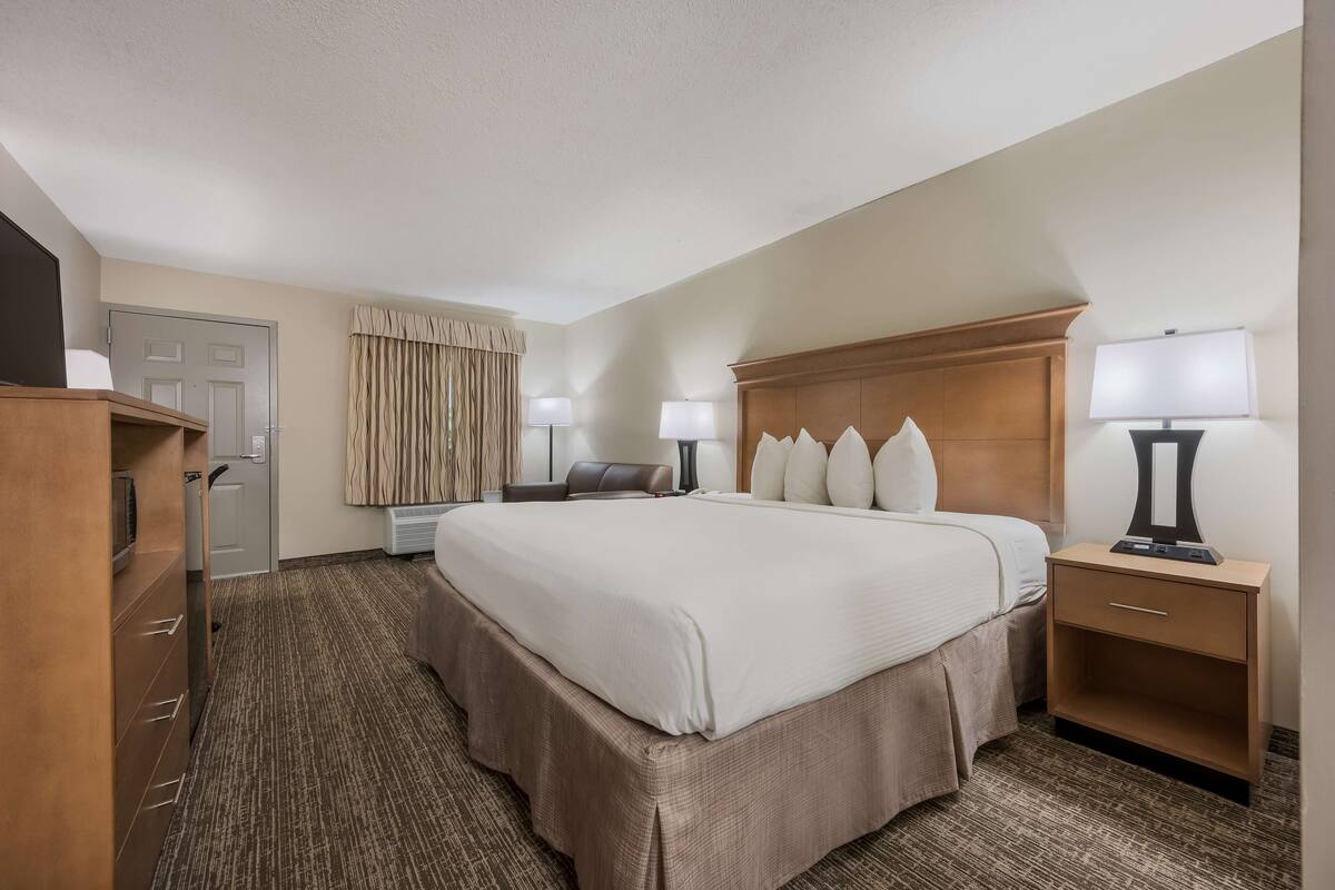 A hotel room with a large bed, bedside lamps, a desk, and a wardrobe.