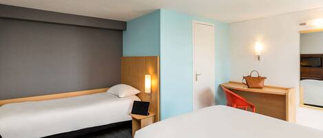 Habitación de hotel con dos camas individuales, un escritorio con silla, una mesita de noche con lámpara y un espejo.