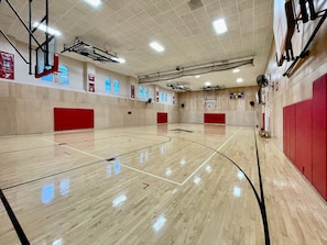 A basketball court with a scoreboard, red padding on walls, and ceiling lights. - Harbor Court Hotel (San Francisco)