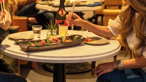 A group of people dining at a restaurant with a table set for a meal, including a bottle of wine and various dishes. - Harbor Court Hotel (San Francisco)