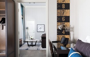 Una sala de estar moderna con piso de madera, un sofá, una mesa de centro y un escritorio con una computadora.