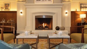 A cozy hotel lobby with a fireplace, two tables with teapots, and comfortable seating. - Harbor Court Hotel (San Francisco)