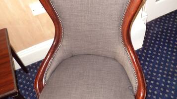 A wooden-framed armchair with a grey upholstered seat and backrest, positioned on a patterned carpet.