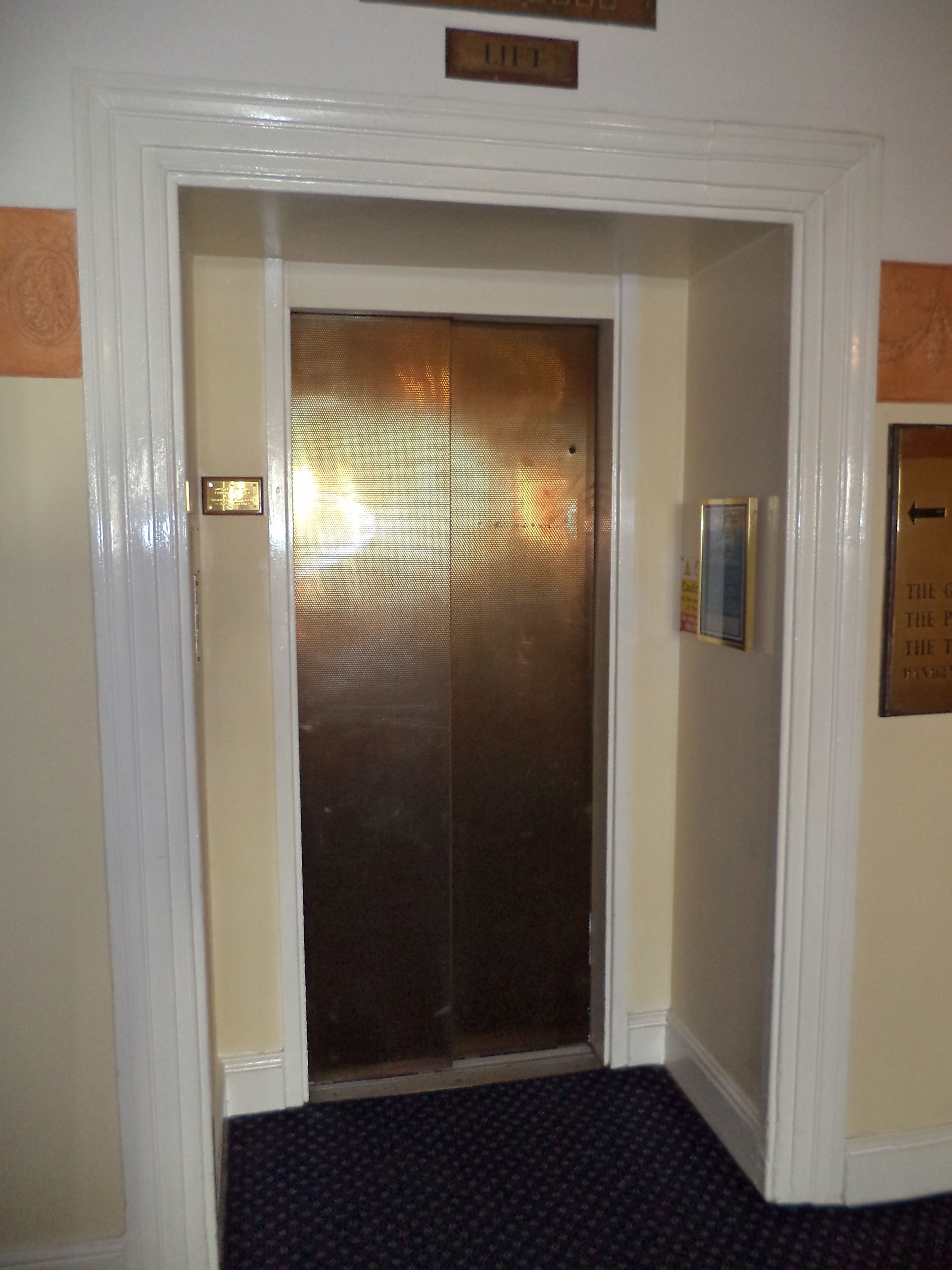 An elevator with a metallic door and a small plaque above it.