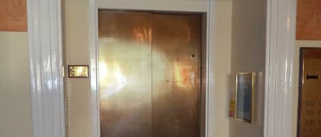 An elevator with a metallic door and a small plaque above it.