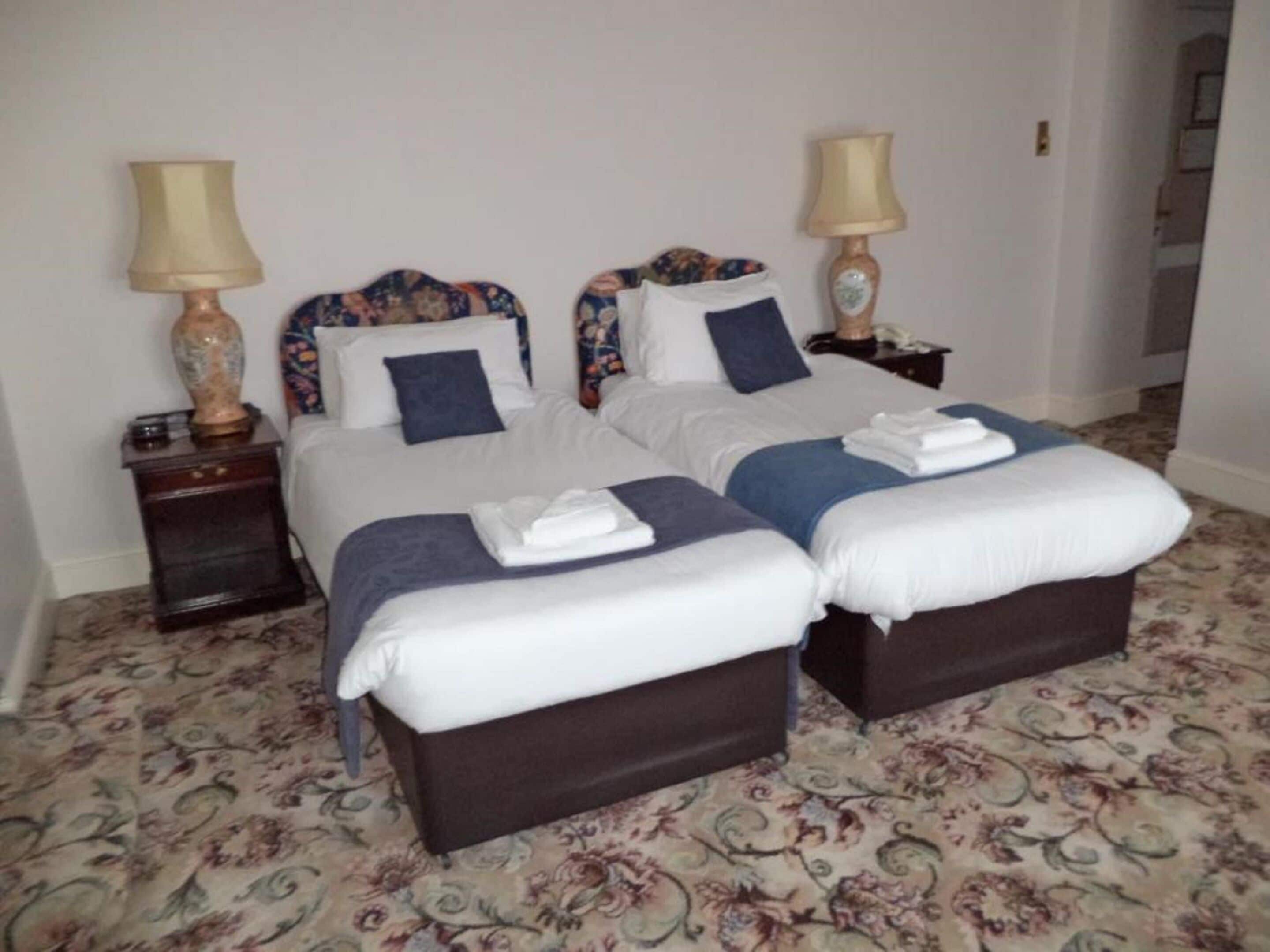 Une chambre avec un grand lit pour deux personnes, deux tables de chevet, chacune équipée d’une lampe et d’un téléphone.