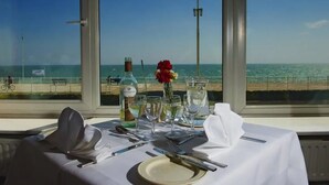 Mesa lista para comer con vista al mar a través de amplios ventanales.