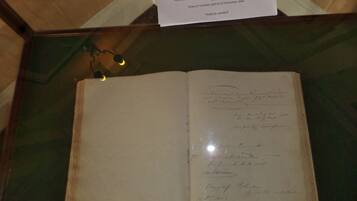 Un libro abierto con texto manuscrito, expuesto en una vitrina de cristal.