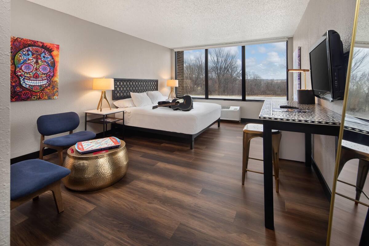 Une chambre d’hôtel moderne, dotée d’un grand lit, d’un bureau, d’une chaise, d’une télévision et d’une fenêtre offrant une vue agréable.