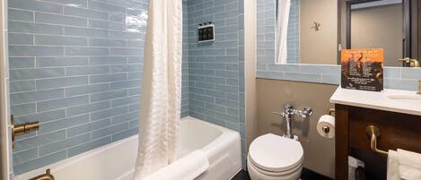 A bathroom with a bathtub, toilet, and vanity with a mirror.
