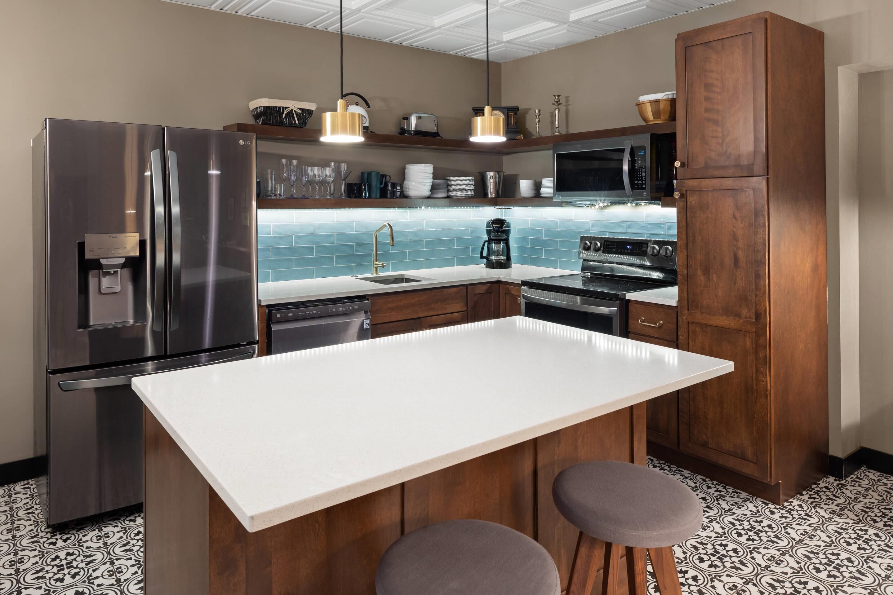 A modern kitchen with a stainless steel refrigerator, a microwave, a coffee maker, and wooden cabinets.