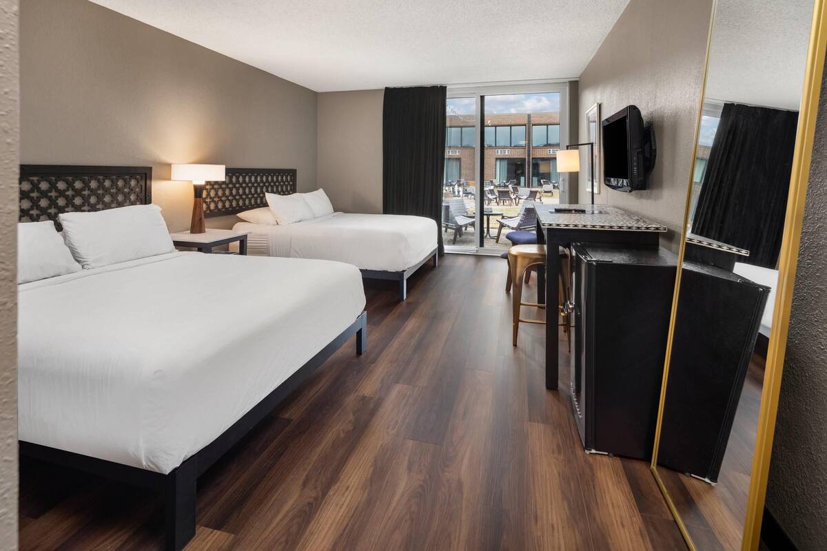 Une chambre d’hôtel avec deux lits, un bureau, une télévision et une vue sur l’extérieur.