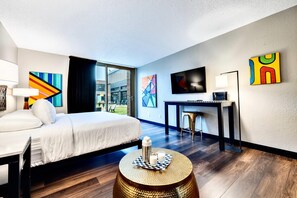A hotel room with a bed, desk, and large windows.