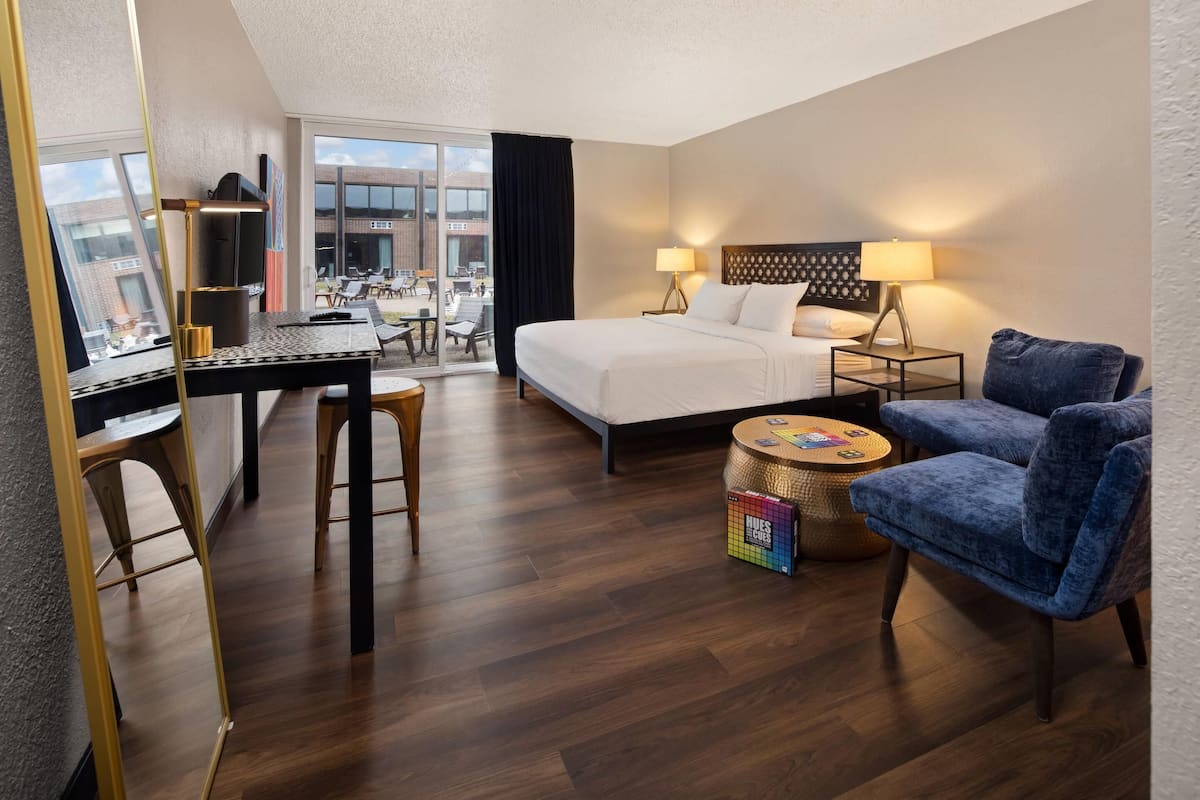 Une chambre d’hôtel comprenant un lit, un bureau, une chaise, une petite table ronde et une vue sur l’extérieur.