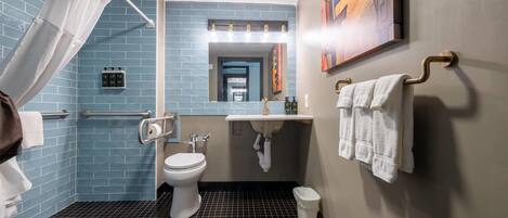 Ein modernes Badezimmer mit einer blauen Fliesenwand, einer weißen Toilette, einem Waschbecken mit Spiegel darüber und einer Duschkabine mit Vorhang.