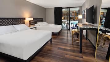 Ein Hotelzimmer mit zwei Betten, einem Schreibtisch, einem Fernseher und einem Balkon mit Pool.