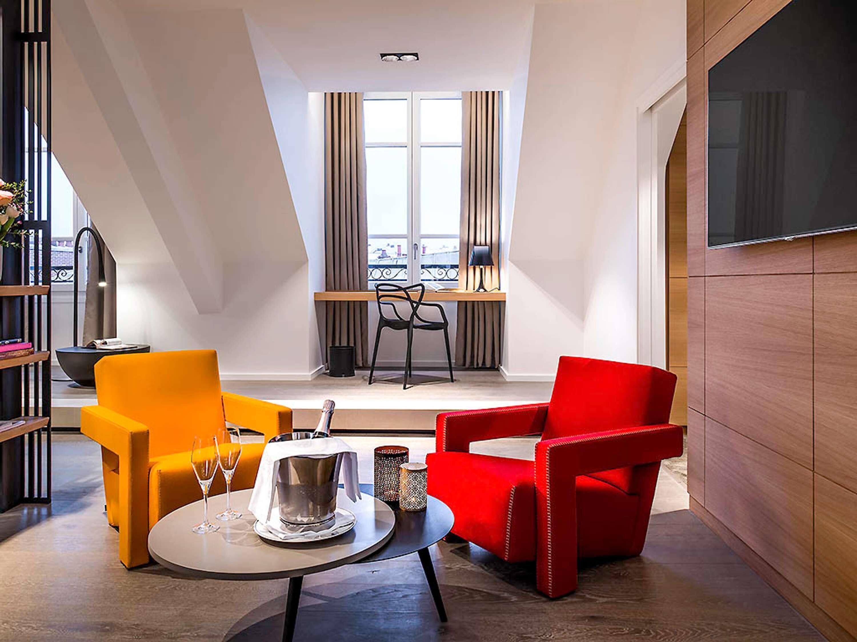 Una sala de estar moderna con una mesa de comedor, dos sillas, un televisor y una ventana con cortinas.