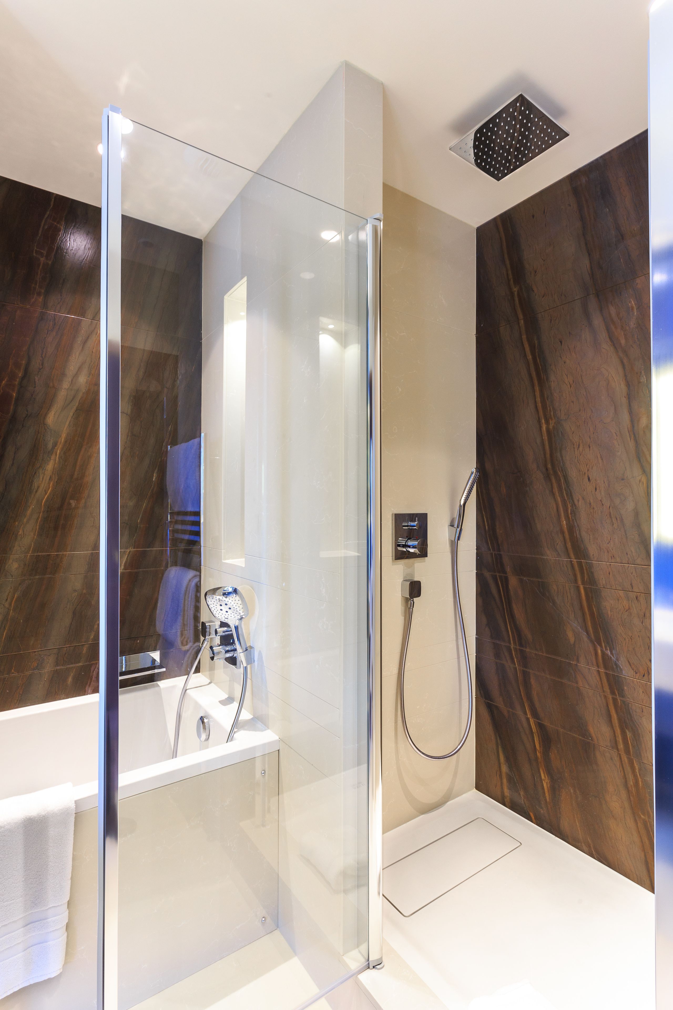 Un baño moderno con cabina de ducha de vidrio, bañera y pared de mármol.