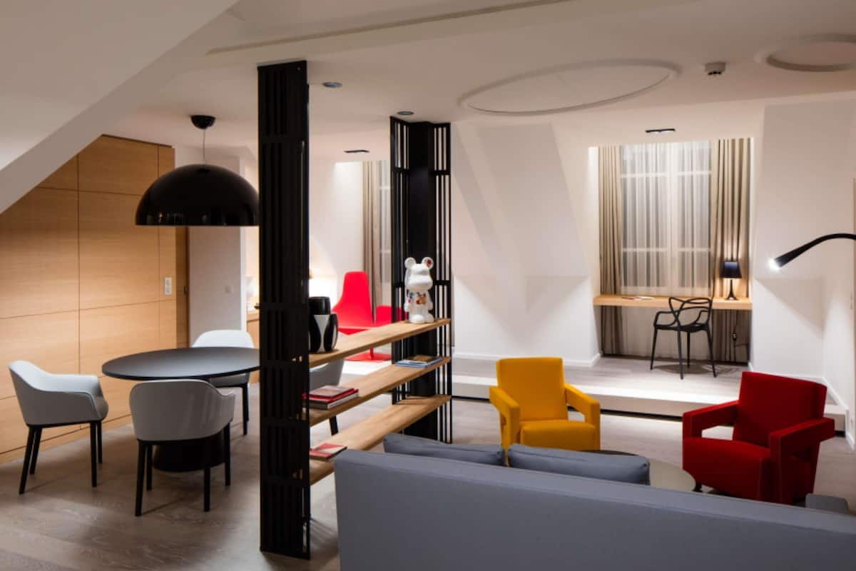 Un salon moderne avec un canapé, des fauteuils, une table et une bibliothèque.