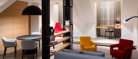 A modern living room with a sofa, chairs, a table, and a bookshelf.