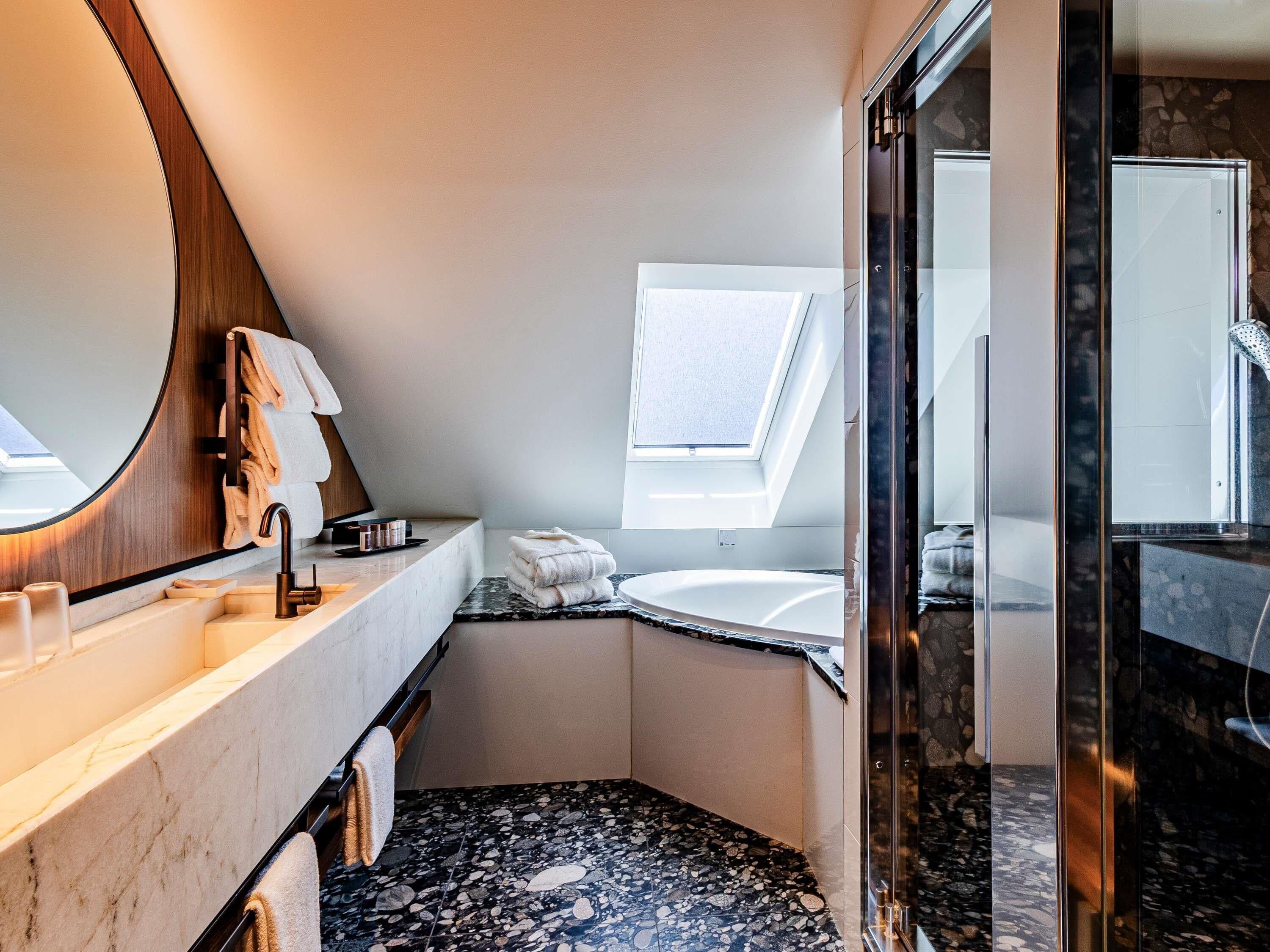 A modern bathroom with a skylight, a freestanding bathtub, and a glass-enclosed shower area.