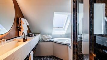 A modern bathroom with a skylight, a freestanding bathtub, and a glass-enclosed shower area.