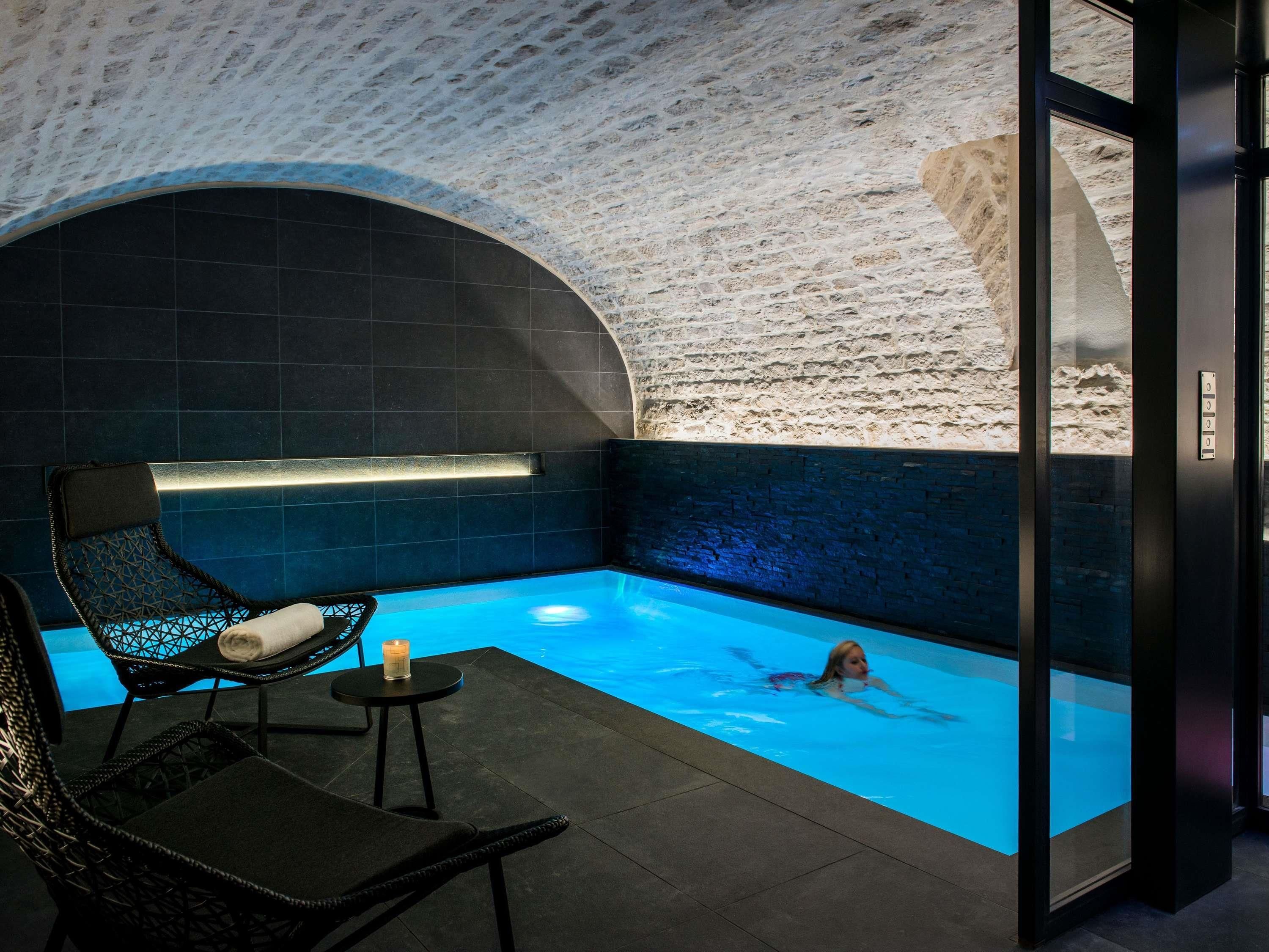 Un espace de détente avec une piscine, un fauteuil et une bougie posée sur une petite table.