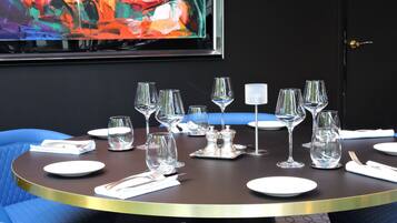 A dining table set with multiple wine glasses, plates, and cutlery, surrounded by blue upholstered chairs.