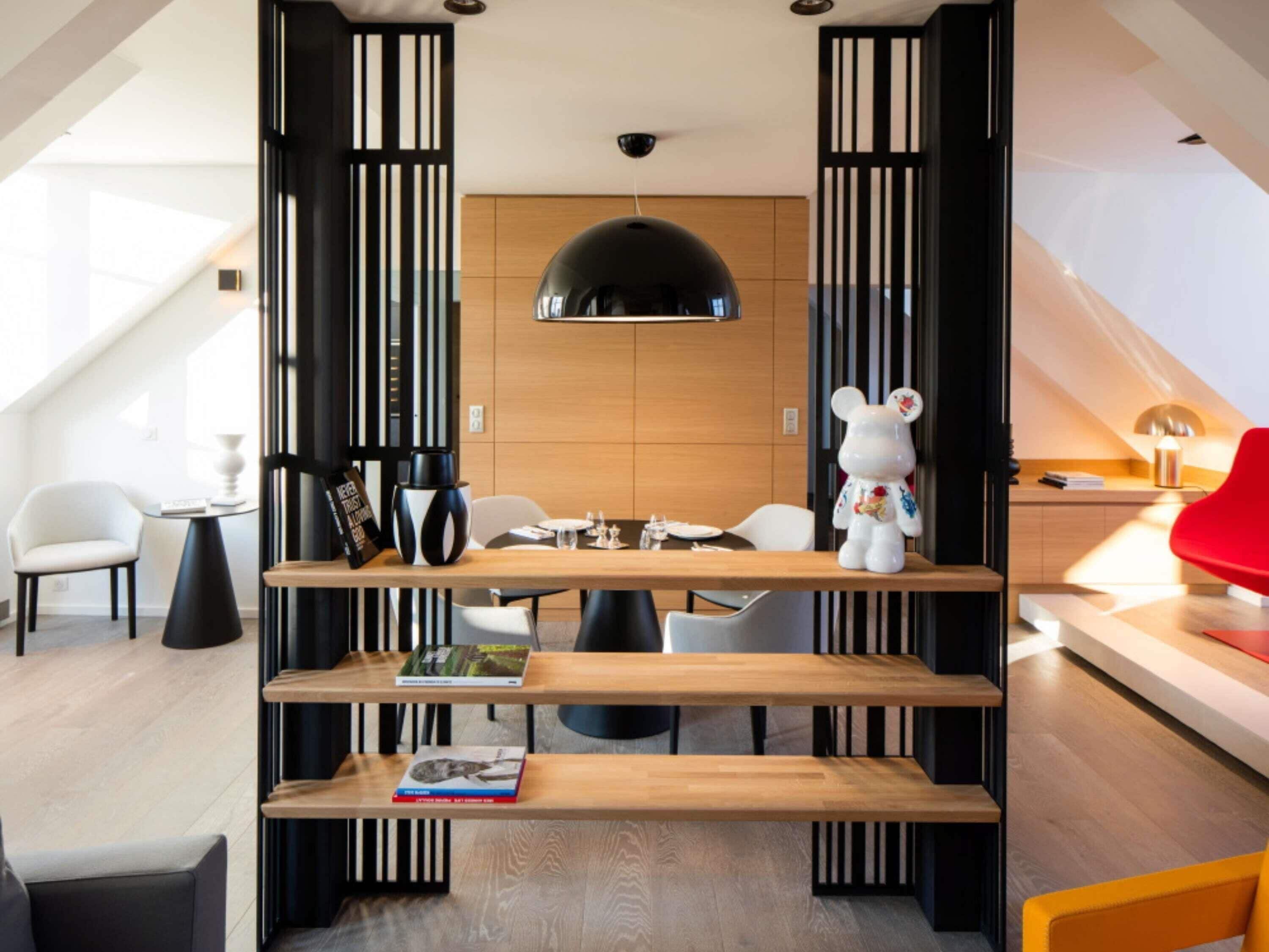A modern dining area with a wooden table, black and white decor, and a red chair.